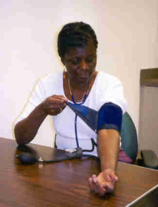 picture of young African-American woman beginning to take her own blood pressure by placing blood pressure cuff snugly around her upper arm